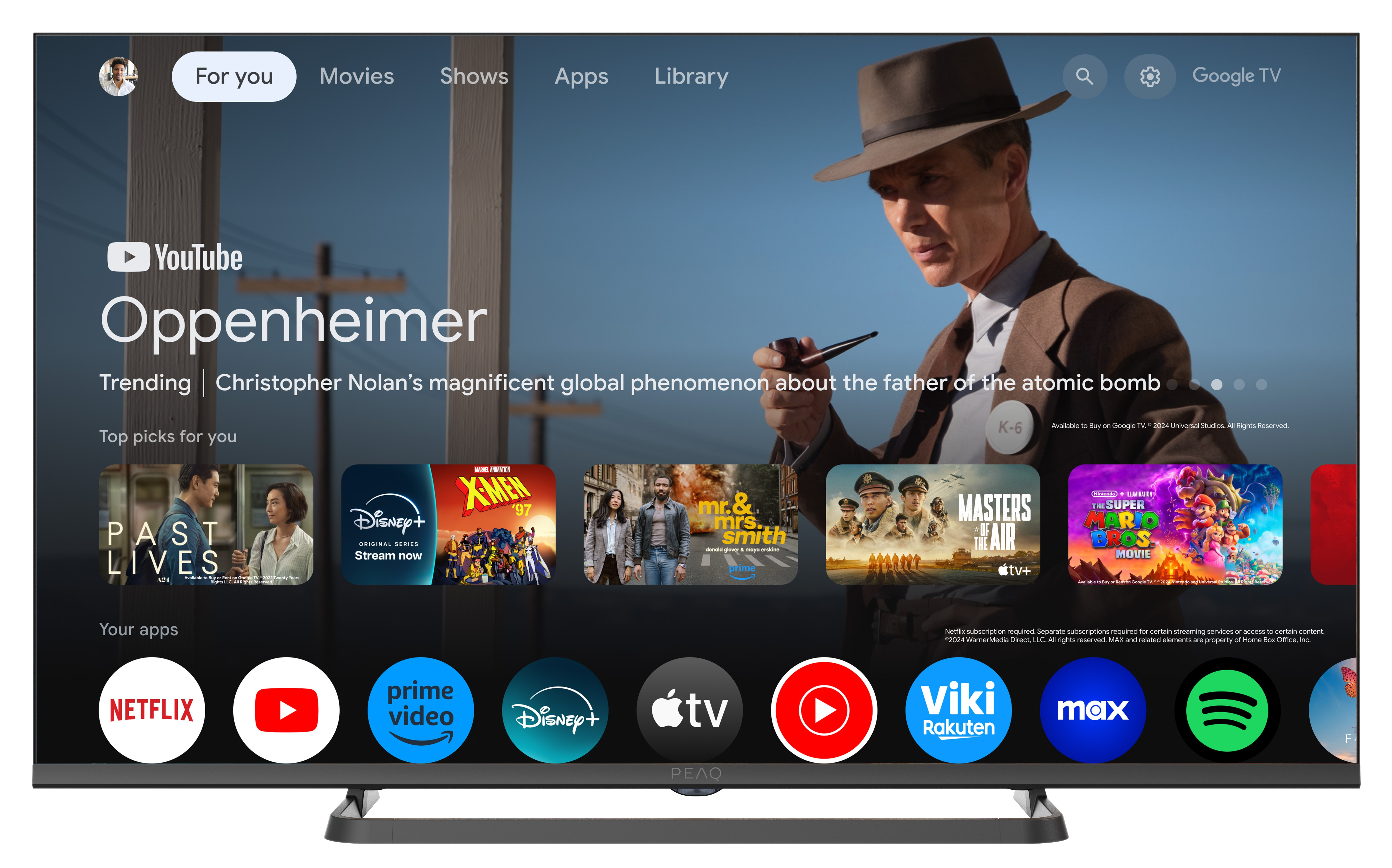 Ekran telewizora wyświetla aplikację YouTube z rekomendacjami filmów i ikonami aplikacji. Prezentowany jest plakat filmu Oppenheimer.
