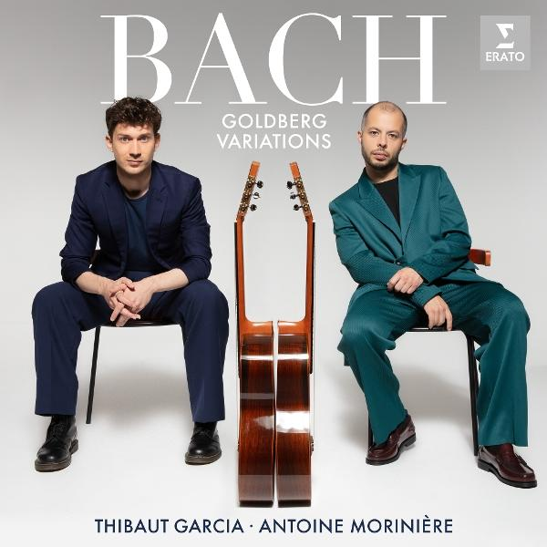 Zwei Männer sitzen mit Gitarren. Einer trägt einen blauen Anzug, der andere einen tealfarbenen Anzug. Bach und Goldberg Variationen stehen oben.