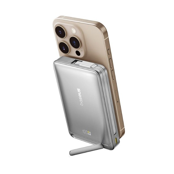 Gümüş bir powerbank, altın rengi bir iPhone'a manyetik olarak takılıdır. Powerbank'in bir standı vardır ve %100 şarjı gösterir.