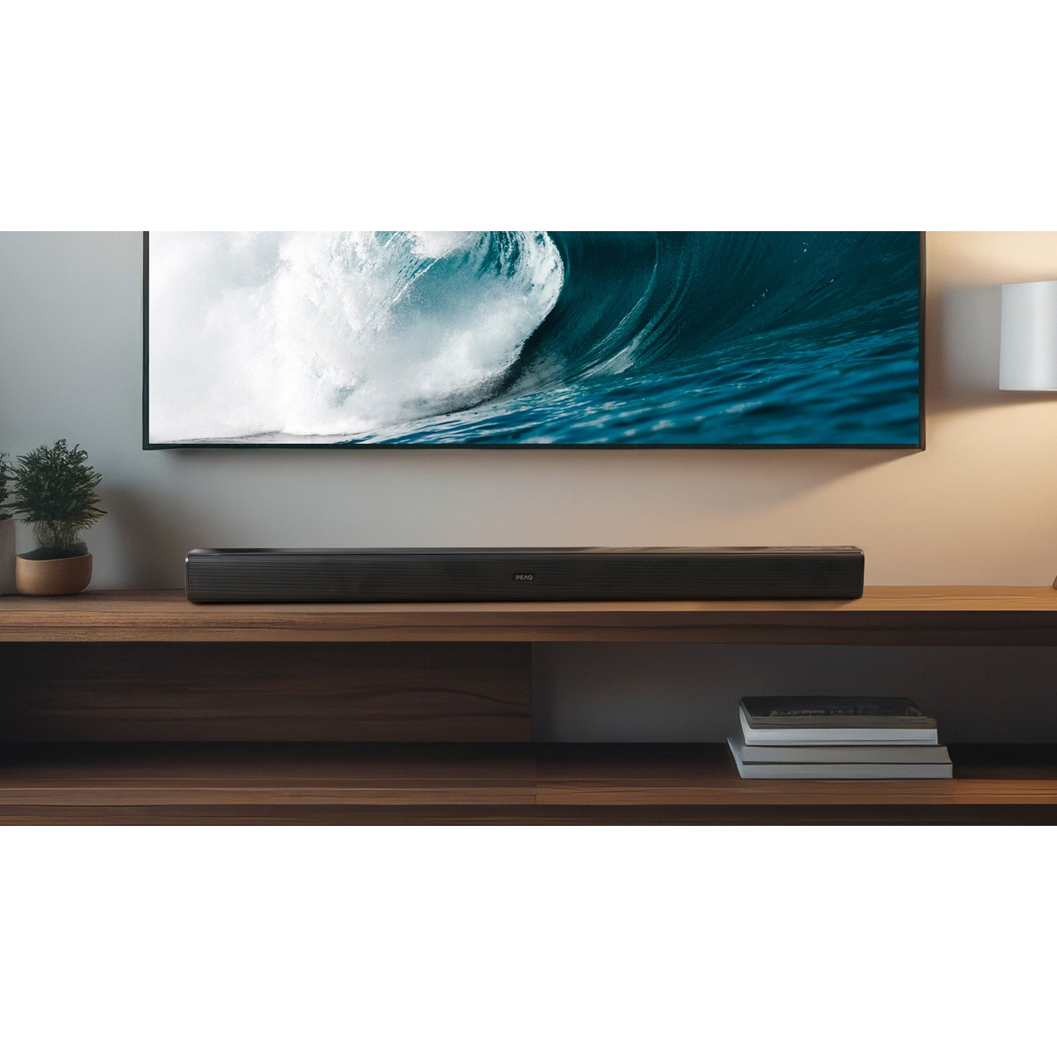 Un televisore che mostra una scena di onde è posizionato sopra una soundbar su una mensola di legno. Anche una piccola pianta e dei libri sono sulla mensola.