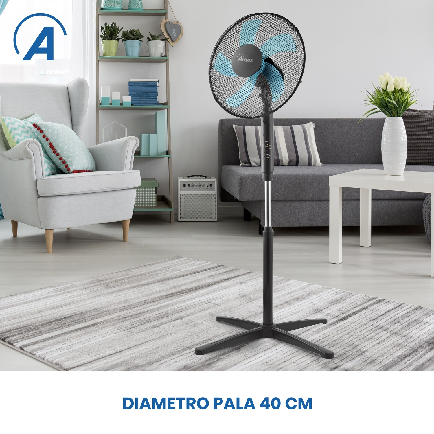 Un ventilatore nero e blu è in un soggiorno. C'è un divano grigio, un tavolo bianco e un tappeto. Una sedia e una mensola sono sullo sfondo.