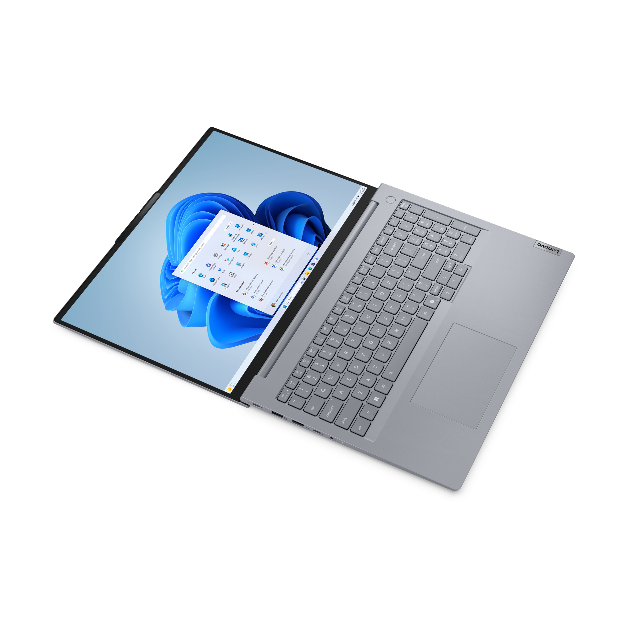 Laptop Lenovo otwarty, pokazujący interfejs Windows 11. Ekran wyświetla niebieskie tło i ikony aplikacji.