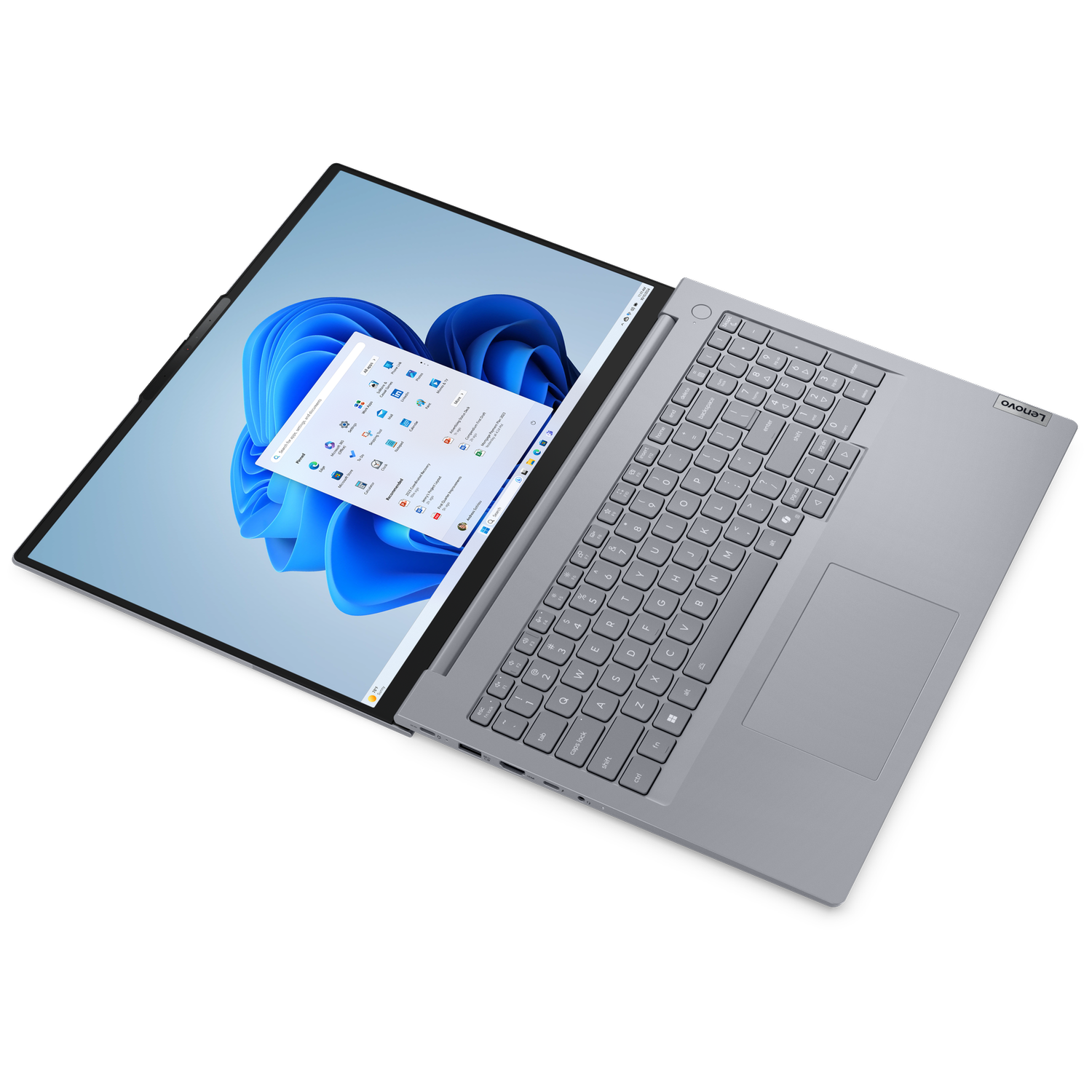 Laptop Lenovo jest otwarty, wyświetlając interfejs Windows 11 z niebiesko-białym tłem. Klawiatura jest widoczna.