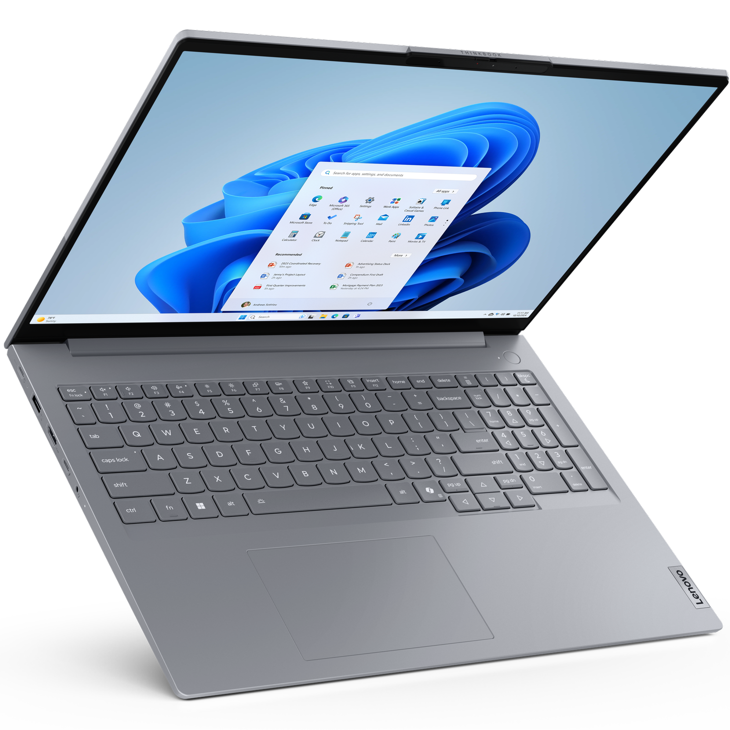 Laptop Lenovo jest otwarty, wyświetlając interfejs Windows 11. Klawiatura i touchpad są widoczne. Tło jest czarne.