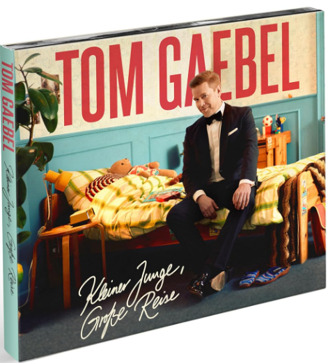 Albumcover zeigt Tom Gaebel im Anzug in einem Kinderzimmer. Der Hintergrund umfasst ein Bett, einen Teddybären und den Text "Tom Gaebel".