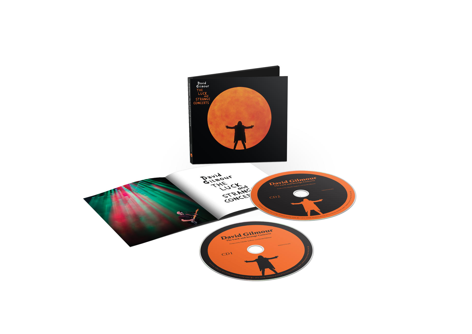 Pochette d'album et CD. La pochette a un cercle orange avec une figure. Les CD ont des figures orange. Le livret montre la scène du concert avec des lumières.