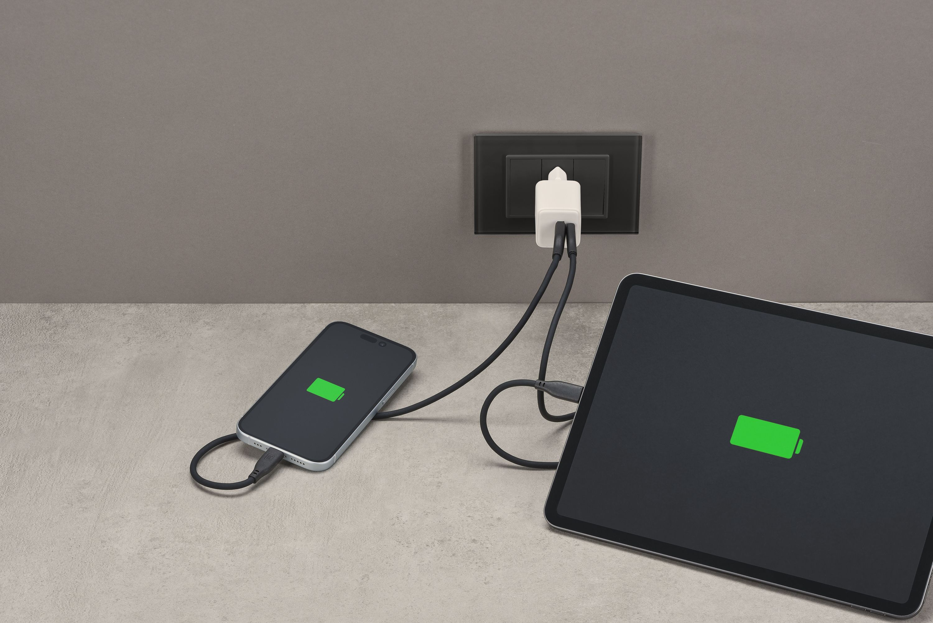 Telefon ve tablet şarj oluyor, ikisi de yeşil pil simgesi gösteriyor. Bir şarj cihazı takılı.