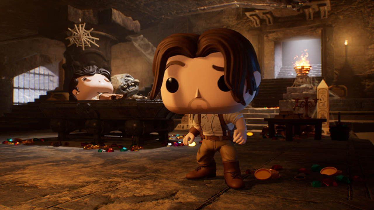 Eine Funko Pop-Figur eines Mannes steht in einer Schatzkammer mit einem Wagen. Eine Frau sitzt im Wagen, auf dem Boden liegen Gold und Edelsteine.