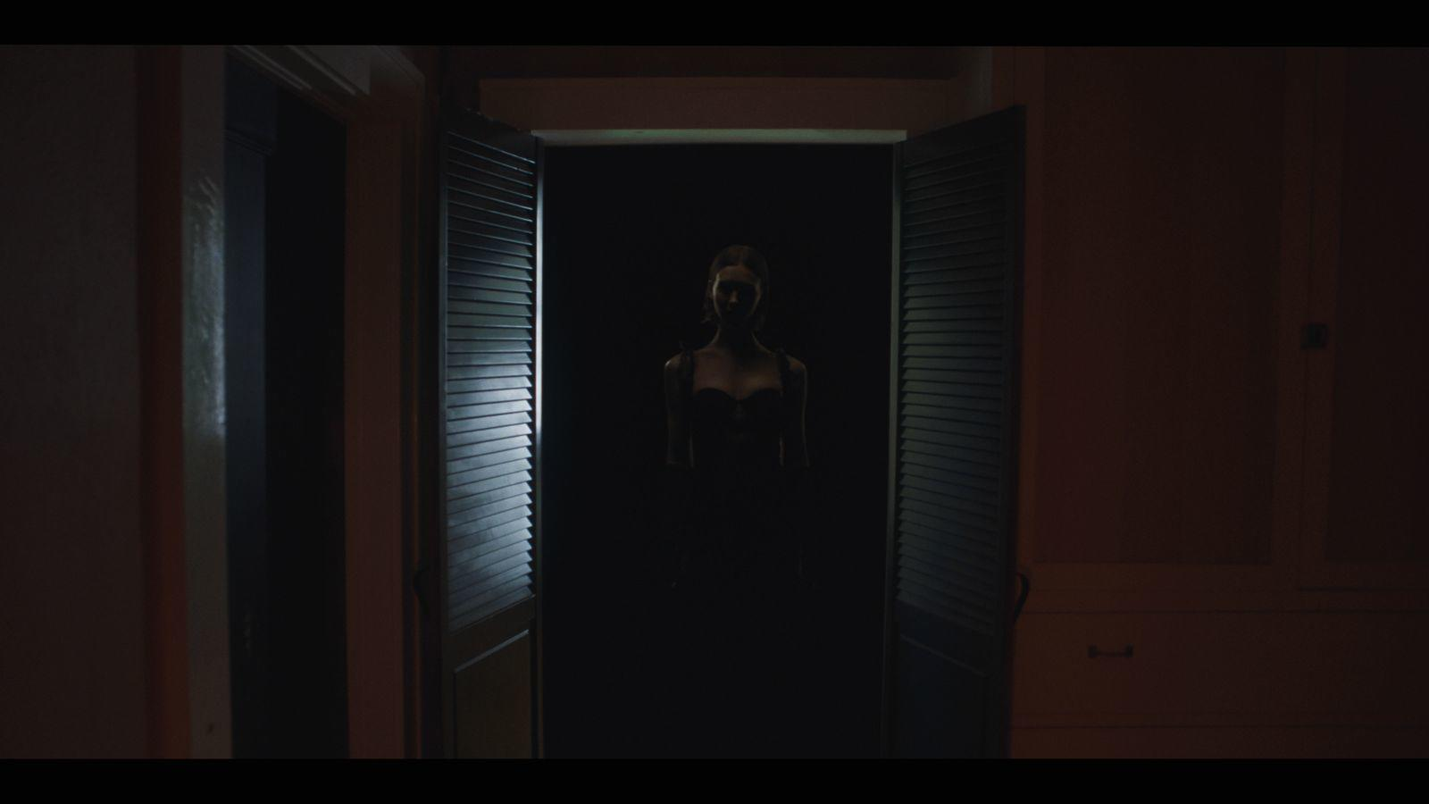 Frau Silhouette im Türrahmen. Dunkler Raum mit geöffneten Fensterläden. Dunkles Kleid. Gedämpftes Licht.