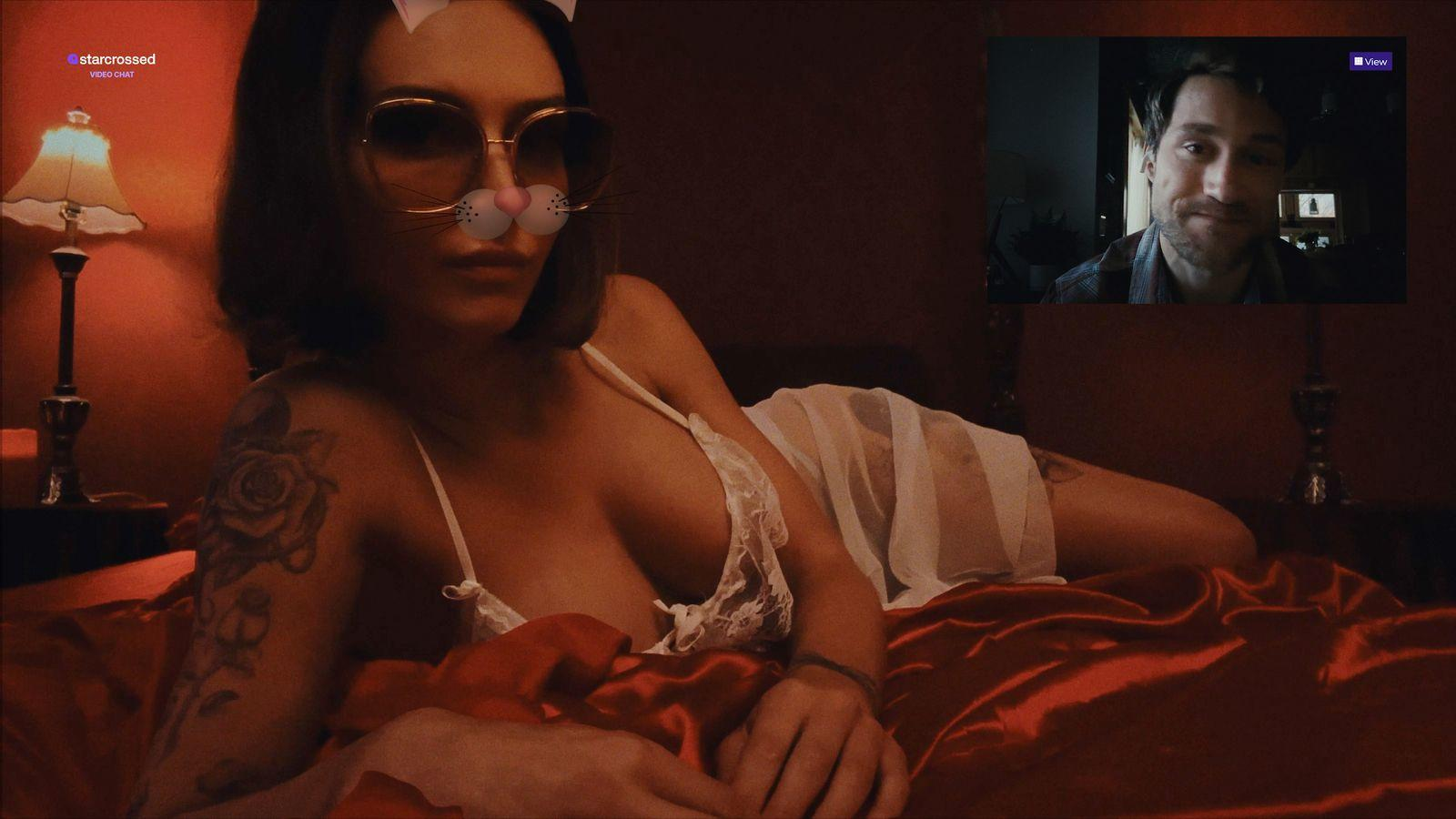 Frau mit Sonnenbrille und Hasenfilter auf rotem Bett, Mann im Videoanruf oben rechts. Links ist eine Lampe.