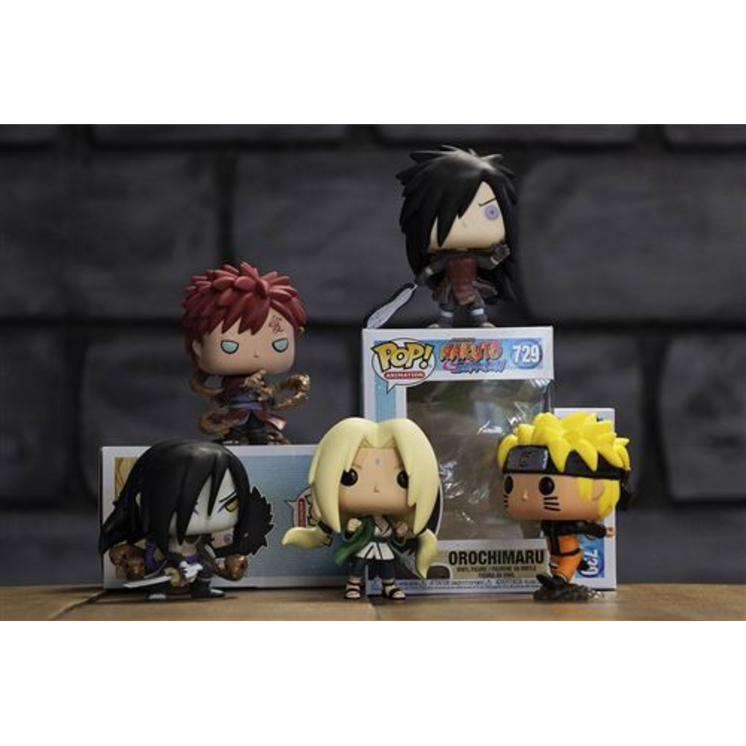 Five Naruto Funko Pop figures on display. Characters include Naruto, Orochimaru, Tsunade, Gaara, and Madara. A box is in the background.