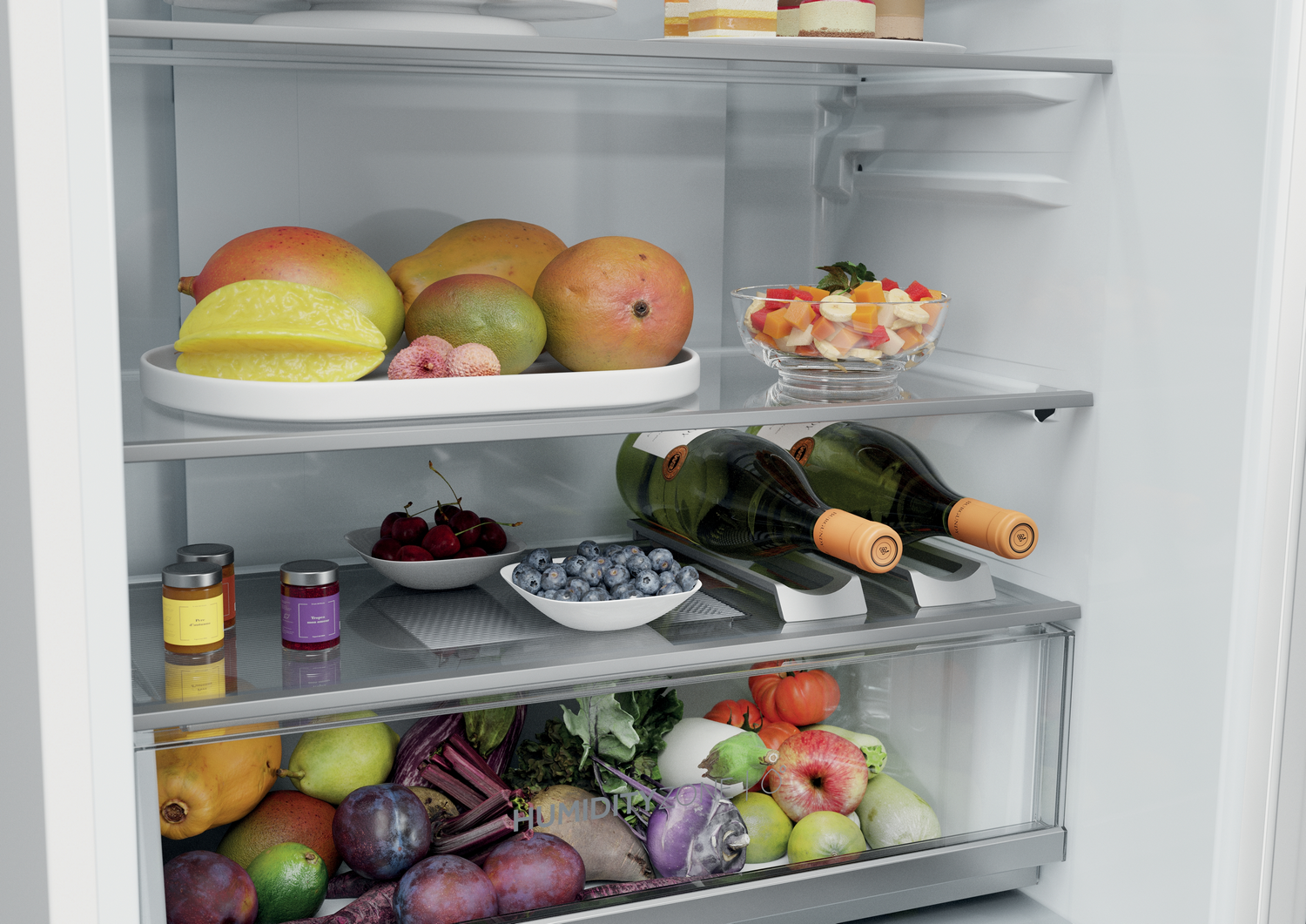 Un refrigerador lleno de frutas, verduras y botellas de vino. Mangos, carambola y una ensalada de frutas están en los estantes.