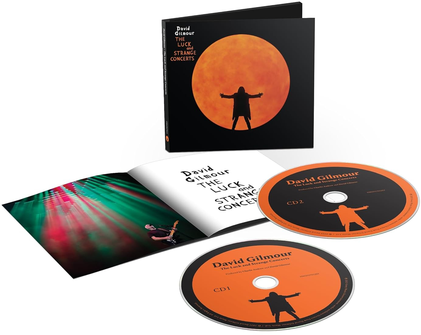 Album borító, CD-k és nyitott füzet. Az album borítója egy karjait felemelő személy sziluettjét mutatja egy narancssárga körrel szemben.