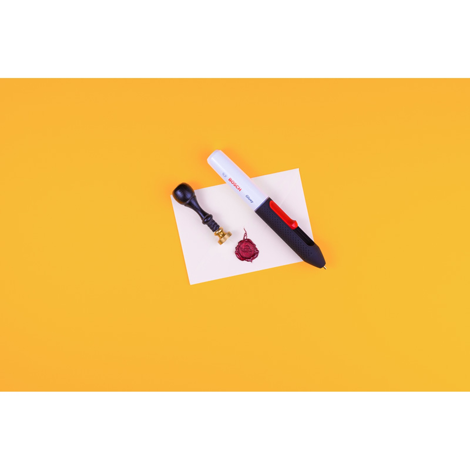 Una penna, un timbro e un sigillo di cera su carta bianca, il tutto su sfondo giallo.