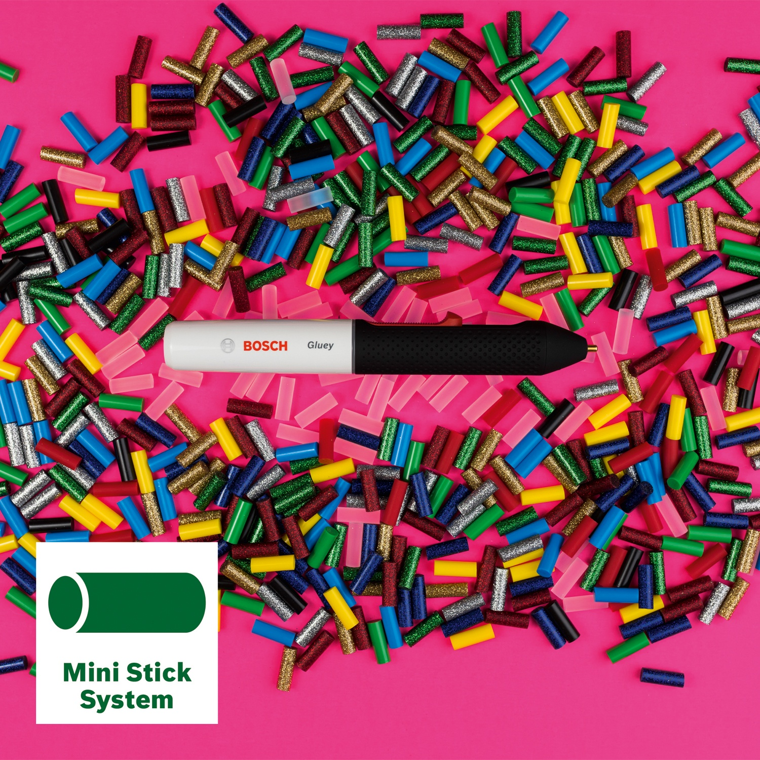 Una pistola per colla Bosch Gluey tra bastoncini colorati su sfondo rosa. Logo Mini Stick System.