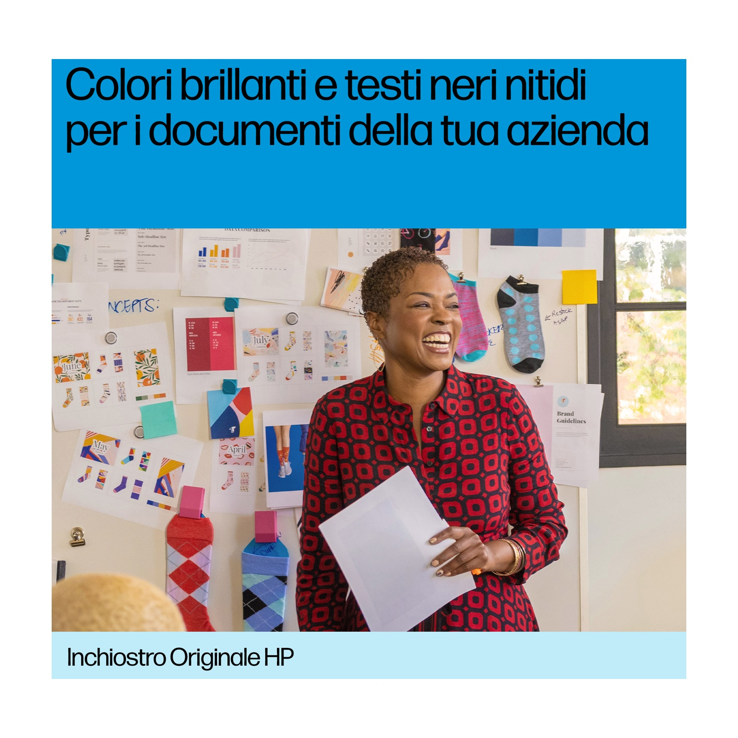 Una donna sorride, tiene dei fogli, vicino a una lavagna con concetti di design e illustrazioni di calzini. Camicia rossa e nera, sfondo blu.