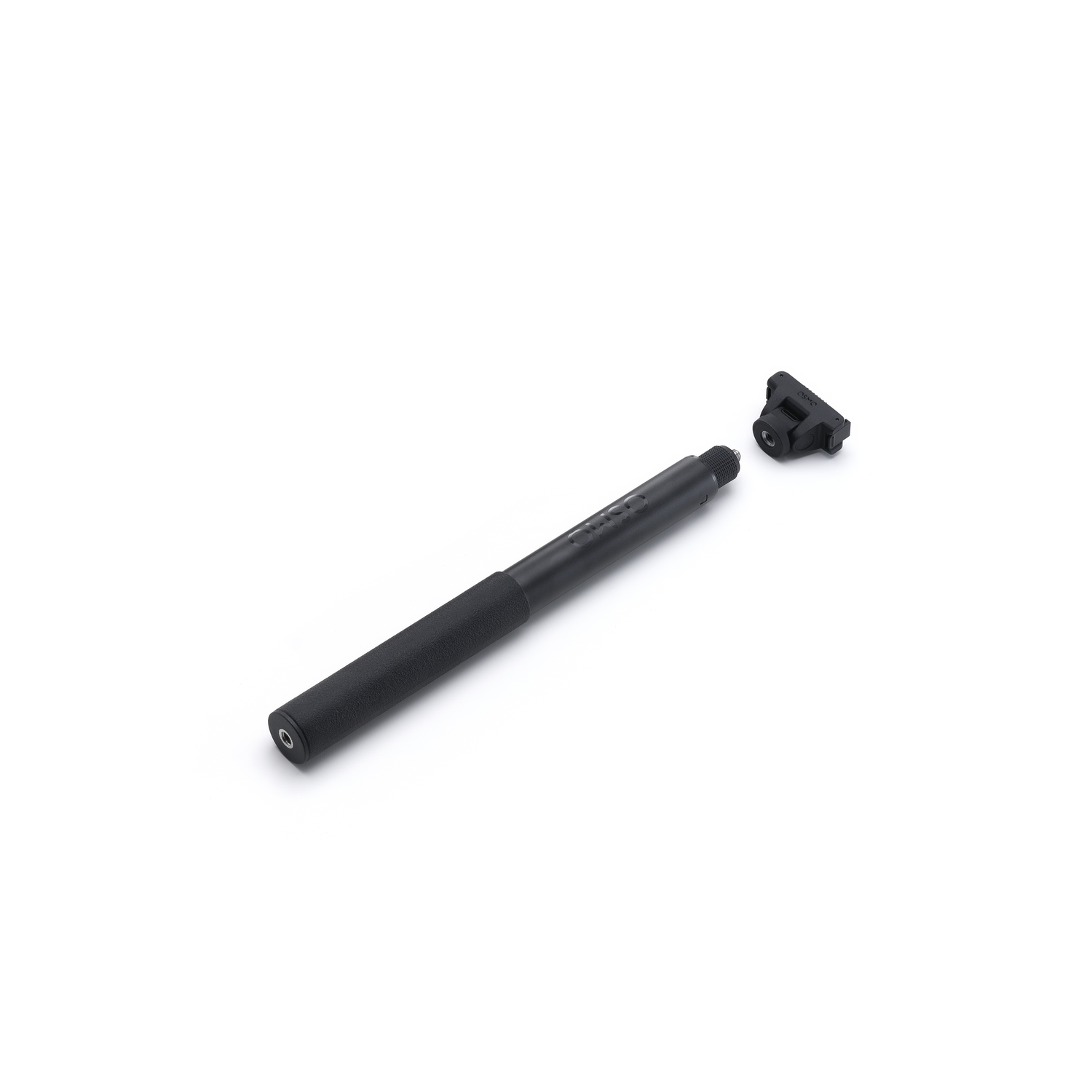 A black selfie stick and a black adapter are lying on a white surface. The stick is long and cylindrical, with a textured grip.
