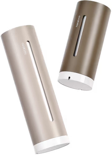 Deux stations météo Netatmo cylindriques. L'une est marron clair, l'autre marron foncé. Les deux ont des bases blanches et des fentes verticales.