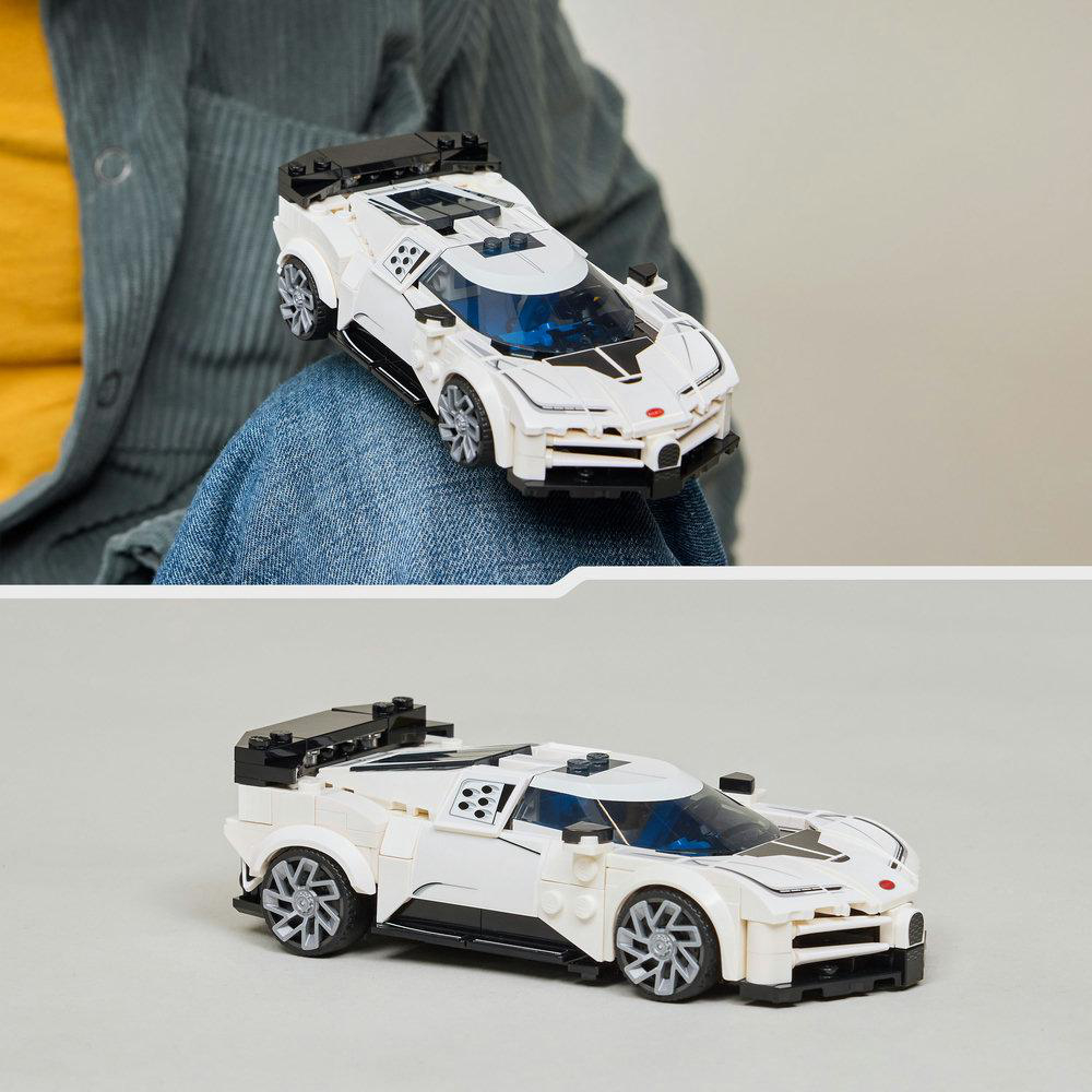 Ein weißes Spielzeugauto mit schwarzen Akzenten wird auf dem Schoß einer Person gehalten. Das Auto ist ein Lego-Modell. Der Hintergrund ist eine verschwommene Person.
