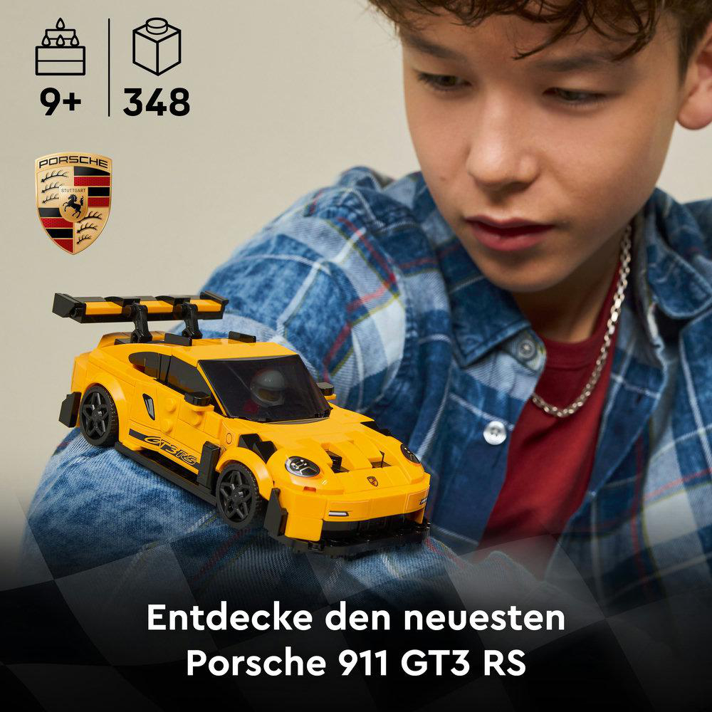 Ein Junge betrachtet ein gelbes Porsche-Modellauto. Das Auto liegt auf seinem Knie. Der Text lautet Porsche 911 GT3 RS.