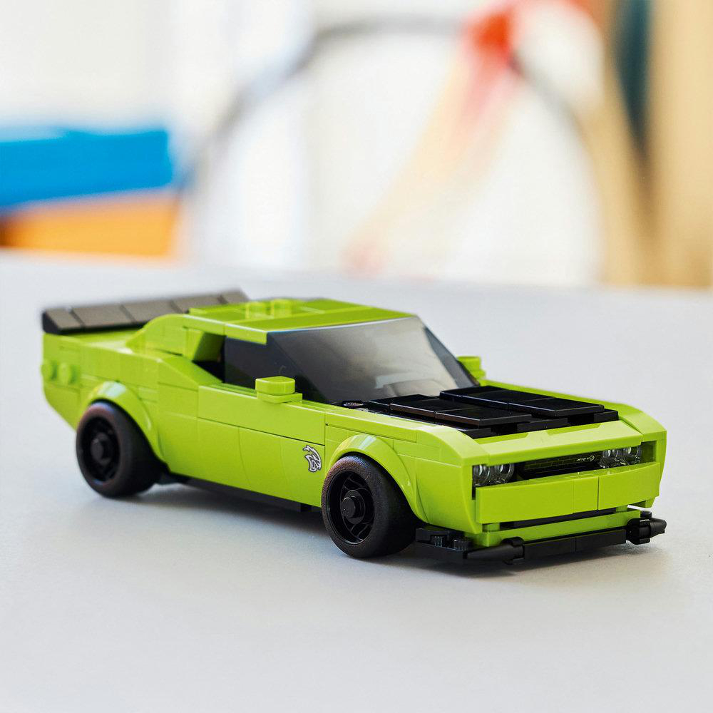 Ein lindgrünes Spielzeugauto steht auf einer hellen Oberfläche. Es hat schwarze Räder und eine schwarze Motorhaube. Der Hintergrund ist unscharf.