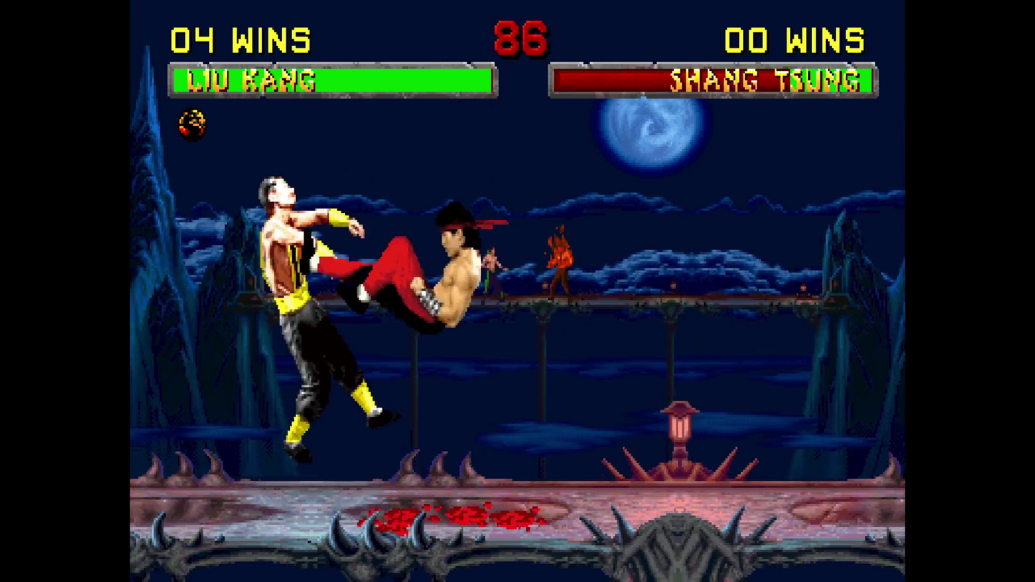 Escena del juego Mortal Kombat. Liu Kang patea a Shang Tsung. El fondo muestra luna, puente y siluetas.