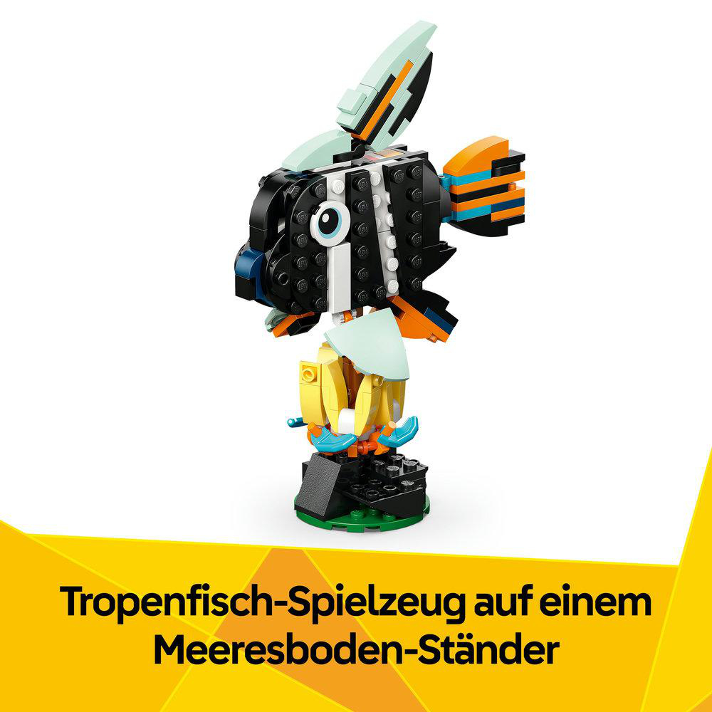 Ein buntes Spielzeugfisch aus Bausteinen mit schwarzen, orangefarbenen, gelben und blauen Teilen, auf einem Ständer. Text darunter lautet 'Tropenfisch-Spielzeug'.
