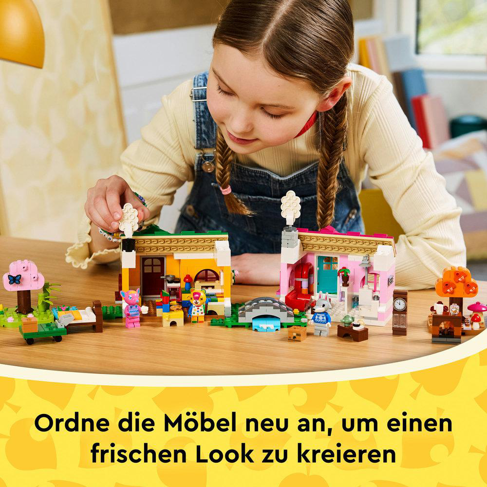 Ein Mädchen spielt mit Lego-Häusern. Verschiedene Lego-Figuren und Zubehör sind auf einem Holztisch angeordnet. Der Text unten sagt 'Räume die Möbel um'.