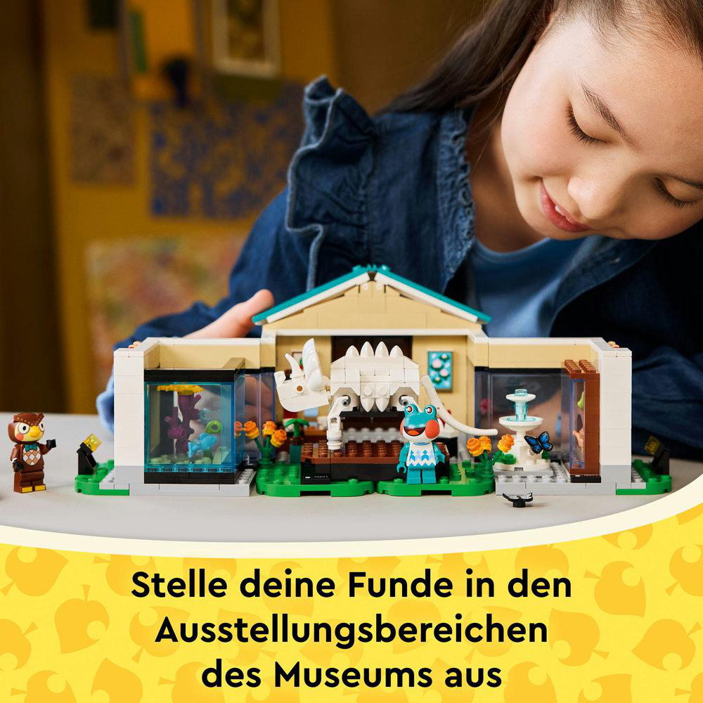 Ein Mädchen betrachtet ein Lego-Museums-Set. Das Set zeigt einen weißen Dinosaurier, einen blauen Frosch und eine kleine Eulenfigur.