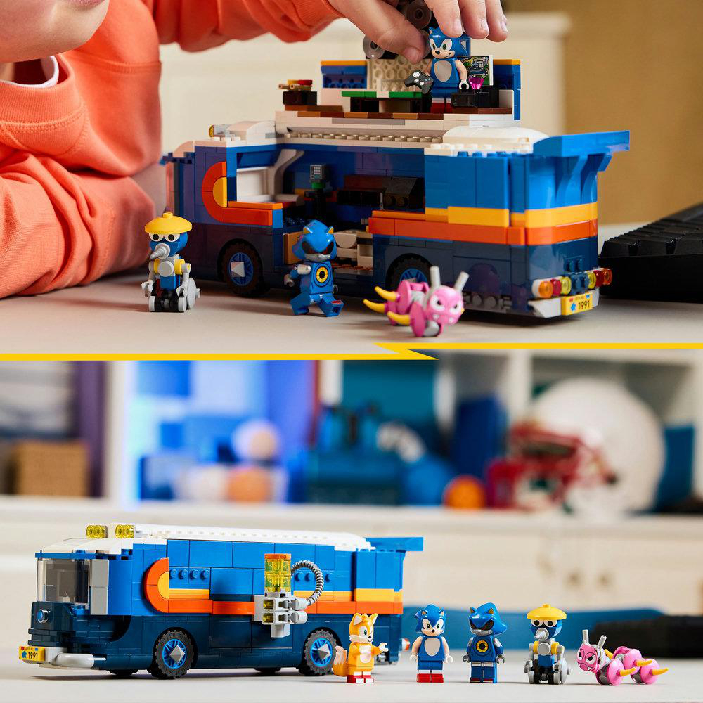 Eine Person spielt mit einem Lego-Set mit Sonic-Charakteren und einem blauen Wohnmobil. Mehrere Figuren und Zubehör sind sichtbar.