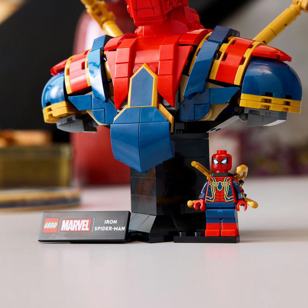 Lego Iron Spider-Man Büste und Minifigur. Die Büste ist rot, blau und gelb. Die Minifigur steht davor auf einem schwarzen Sockel.