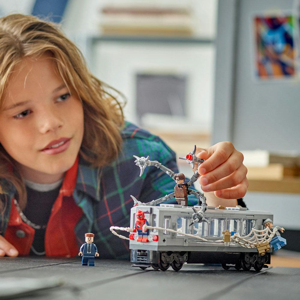 Ein Kind spielt mit einem Lego-Set mit Spider-Man und Doctor Octopus Figuren auf einem Waggon.