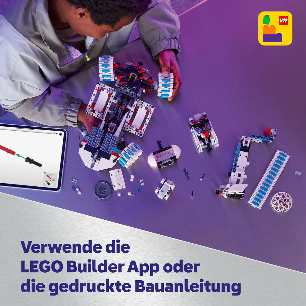 Eine Person montiert ein LEGO-Set. Teile liegen auf einem Tisch verstreut. Ein Tablet zeigt Anweisungen. LEGO-Logo rechts oben.