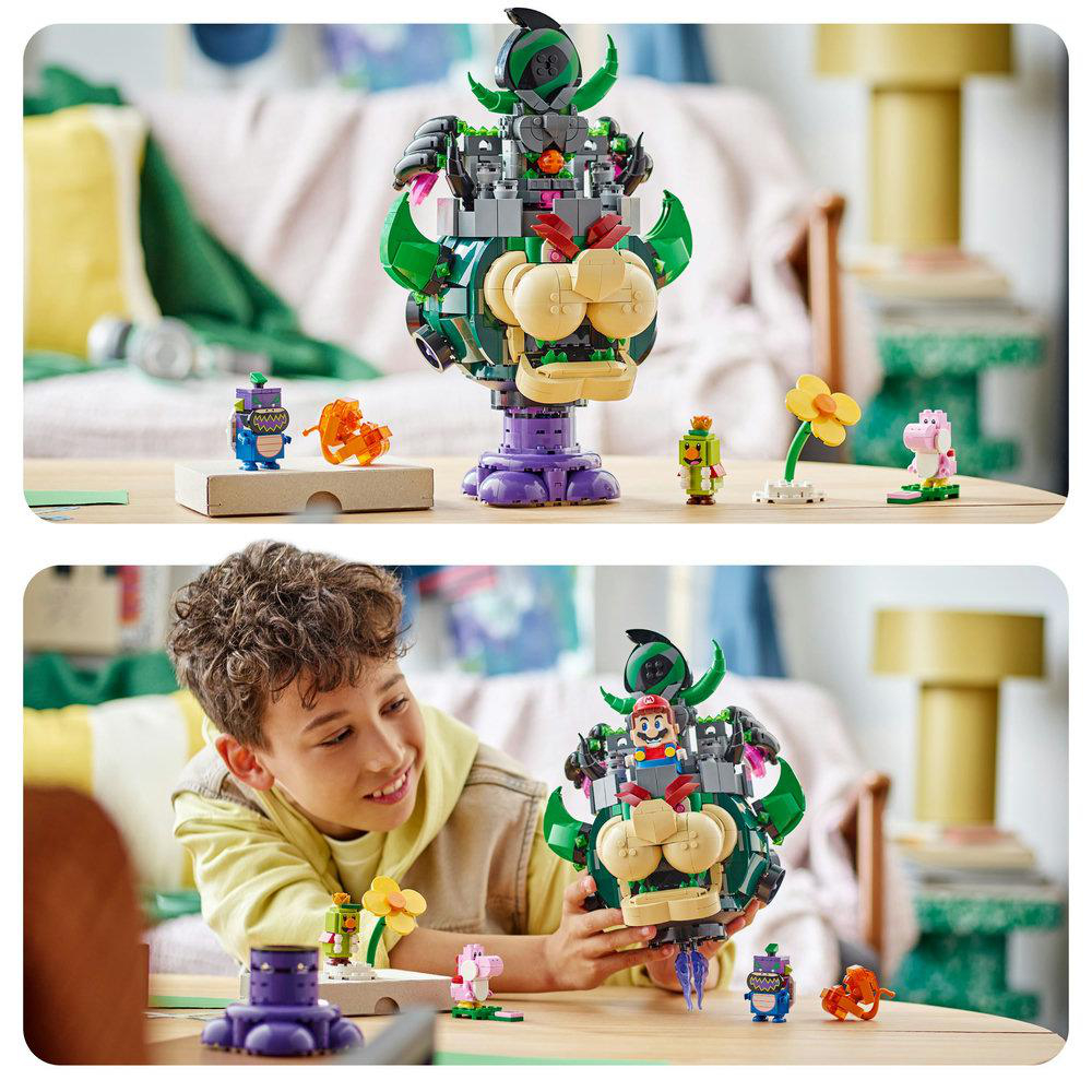 Ein Junge lächelt und hält einen Lego-Bowser. Daneben sind Lego-Figuren und eine Blume auf einem Tisch ausgestellt. Der Hintergrund umfasst eine Couch.