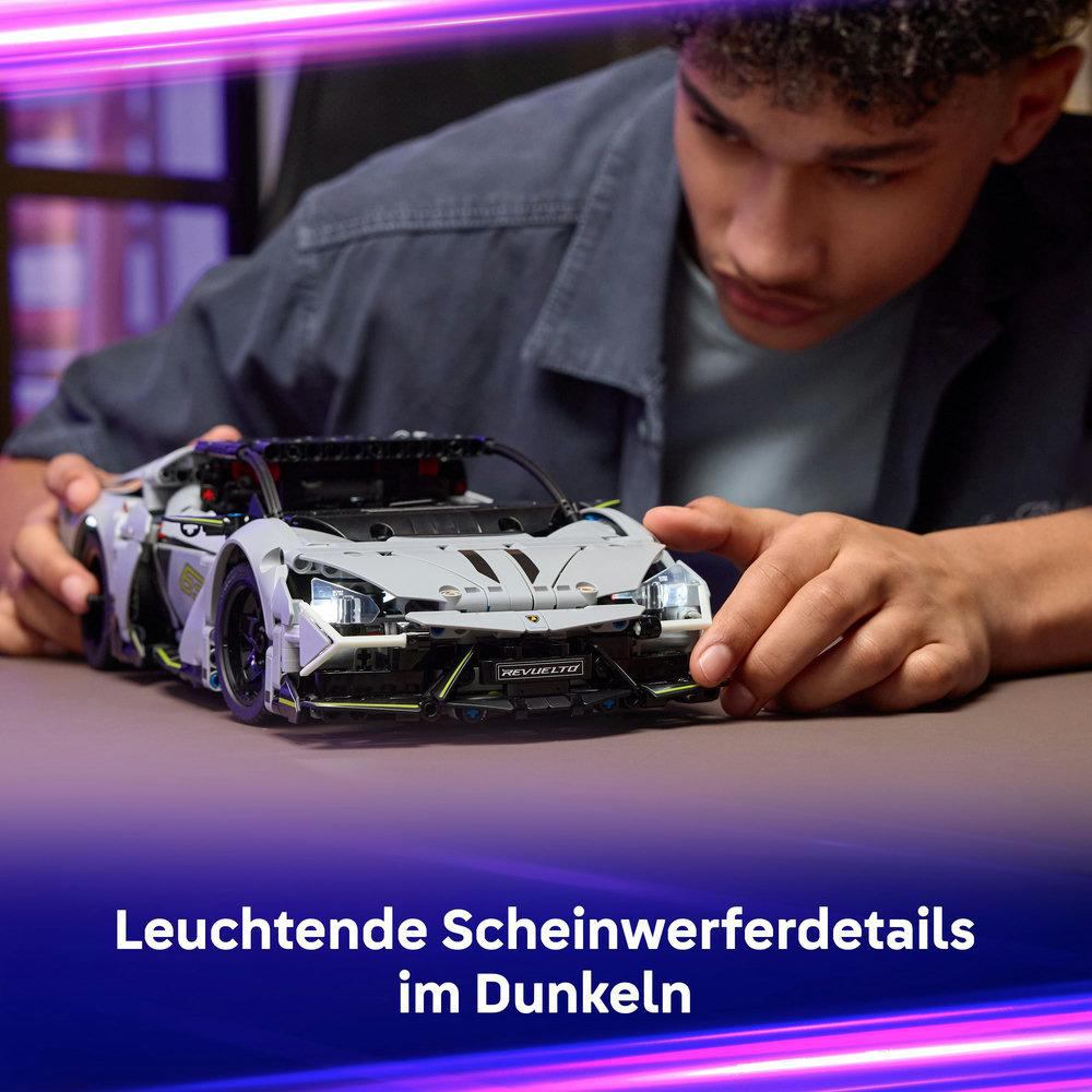 Eine Person betrachtet ein graues Spielzeug-Sportwagen mit der Aufschrift 'REVUELTO'. Das Auto steht auf einer braunen Oberfläche.