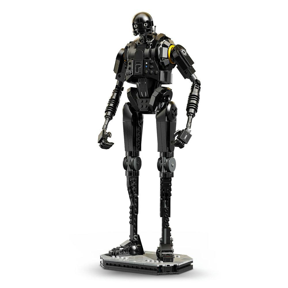 Eine schwarze K-2SO-Lego-Figur steht auf einer grauen Basis. Sie hat einen schwarzen Kopf mit zwei augenartigen Sensoren und mechanischen Gliedmaßen.
