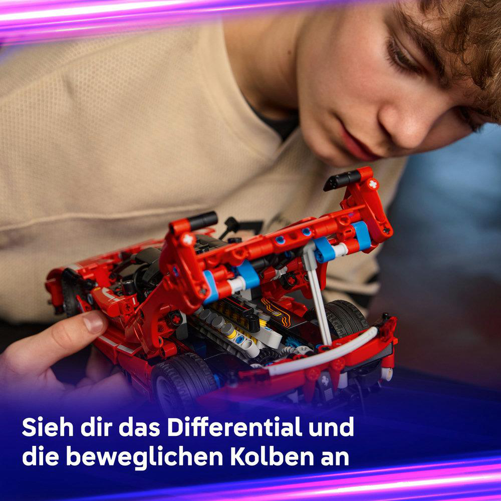Ein junger Mensch hält ein rotes Spielzeugauto und untersucht dessen innere Komponenten. Die Szene ist gut beleuchtet, mit Fokus auf das Auto und die Person.