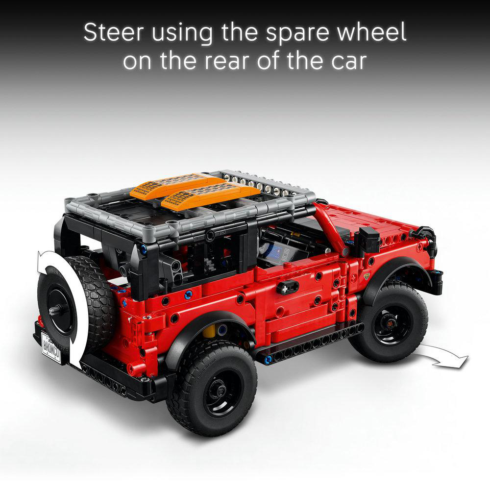 Ein rotes Spielzeugauto mit Ersatzreifen, Pfeile zeigen darauf, und Text, der anweist, mit dem Ersatzrad zu lenken.