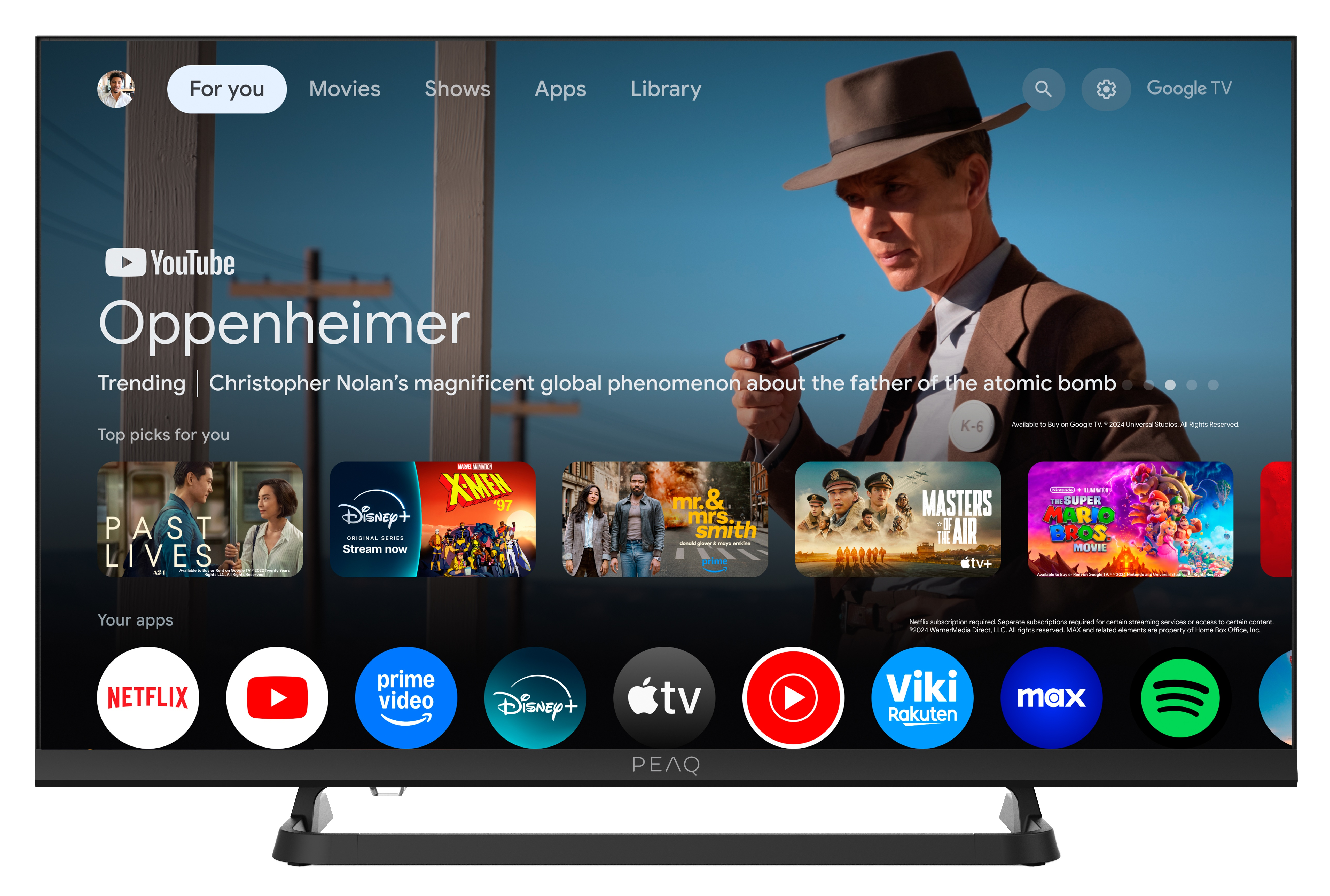 Ekran telewizora wyświetla aplikację YouTube z 'Oppenheimer' i sugestiami filmów. Kilka ikon aplikacji jest widocznych na dole.