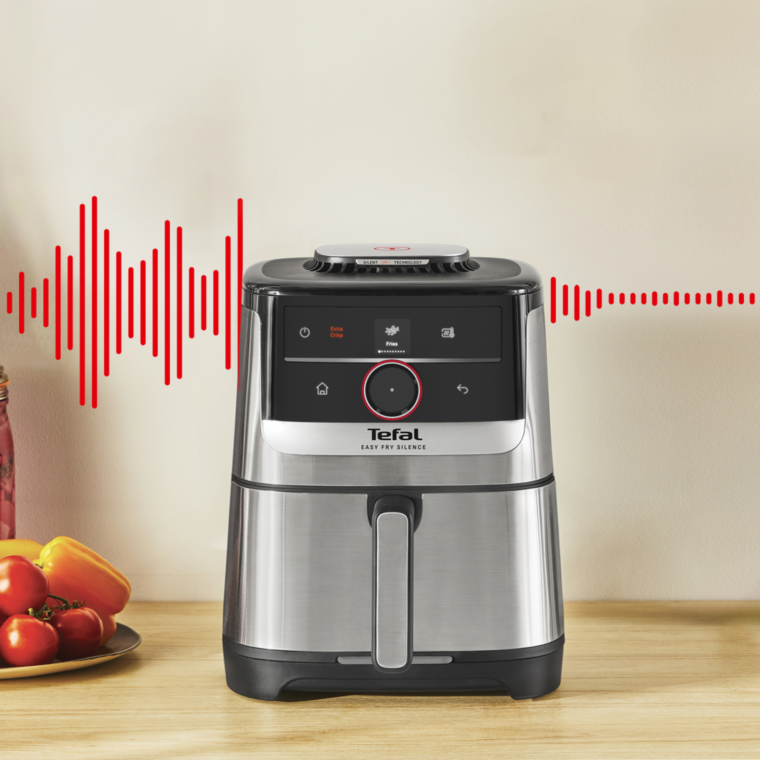 An air fryer with a red soundwave graphic. Vegetables in a plate are in the foreground. The appliance has the Tefal brand.