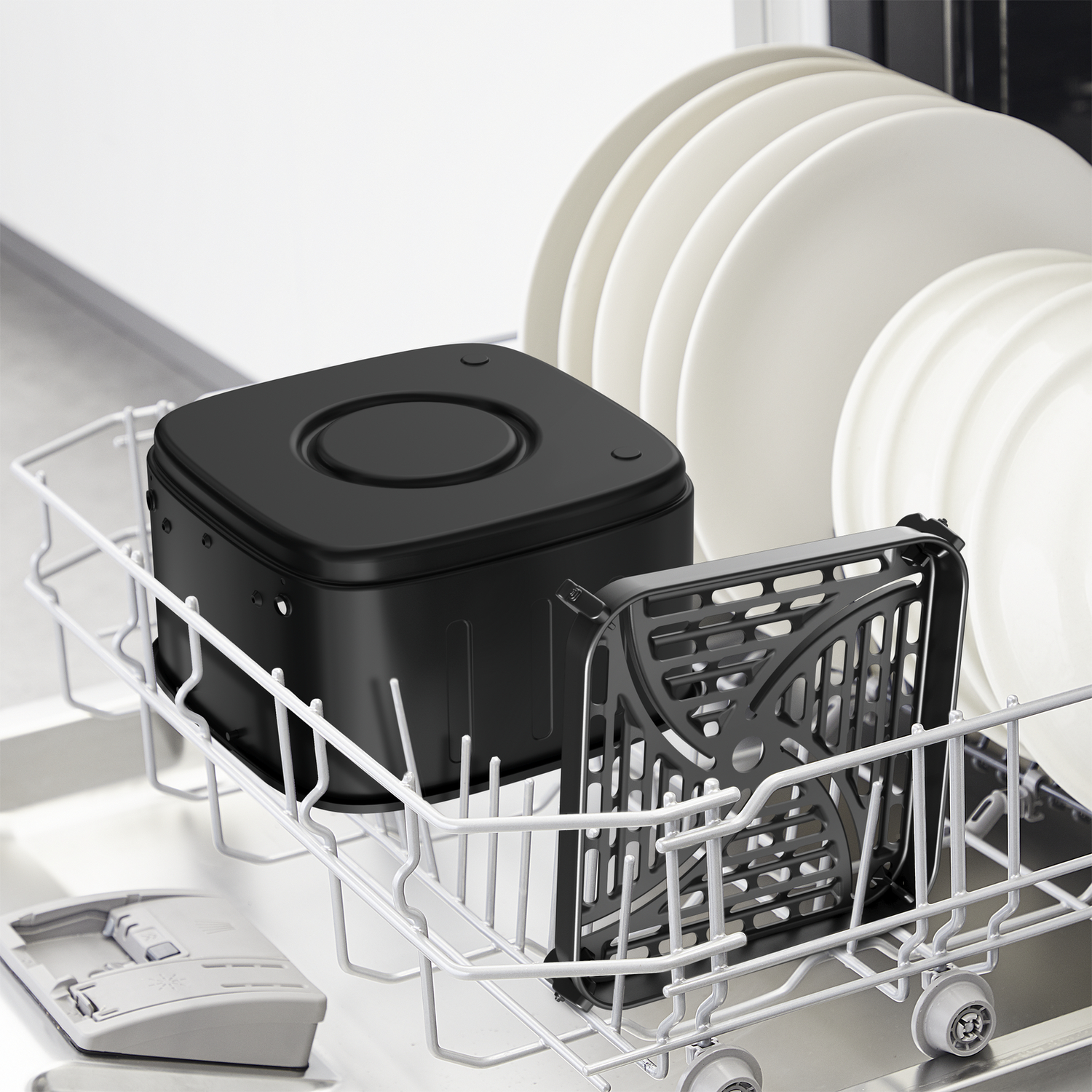 Black air fryer parts and white plates are in a dishwasher. Gray and white dishwasher interior. Black tray in the foreground.