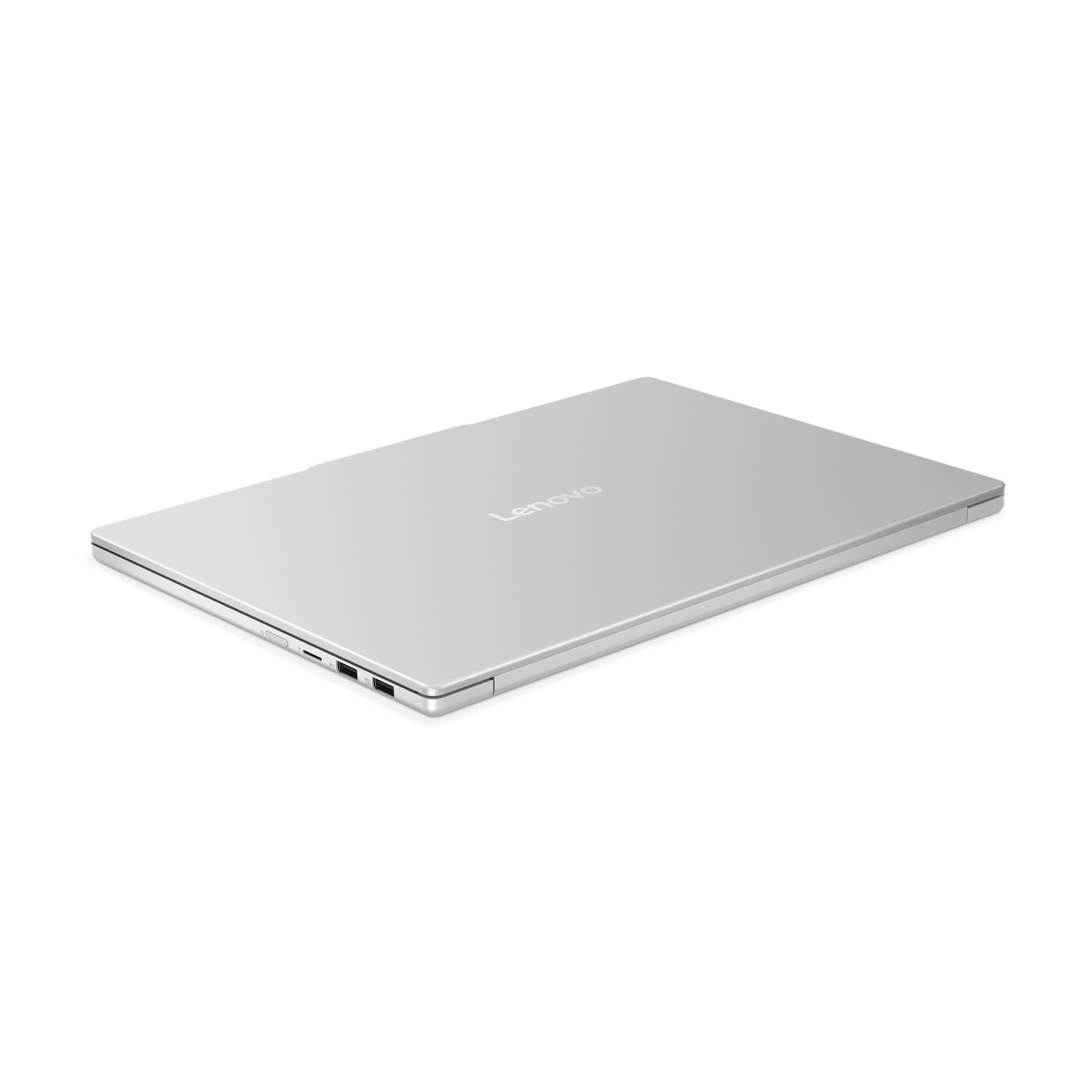 Un ordinateur portable Lenovo argenté est fermé et légèrement incliné. Le logo Lenovo est visible. Le fond est blanc.