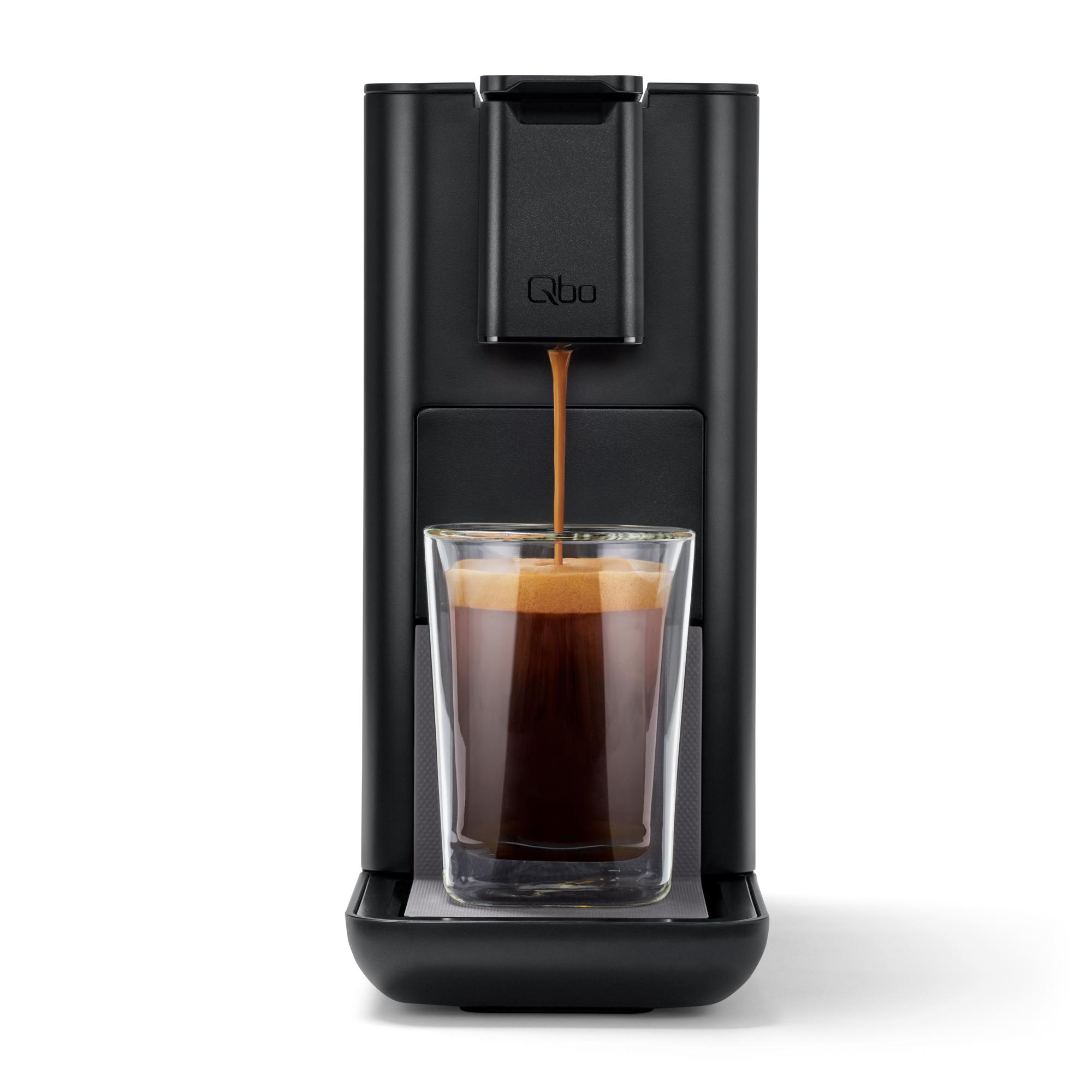 Eine schwarze Kaffeemaschine, die Kaffee in ein Glas ausgibt. Der Kaffee ist dunkelbraun und hat Schaum.