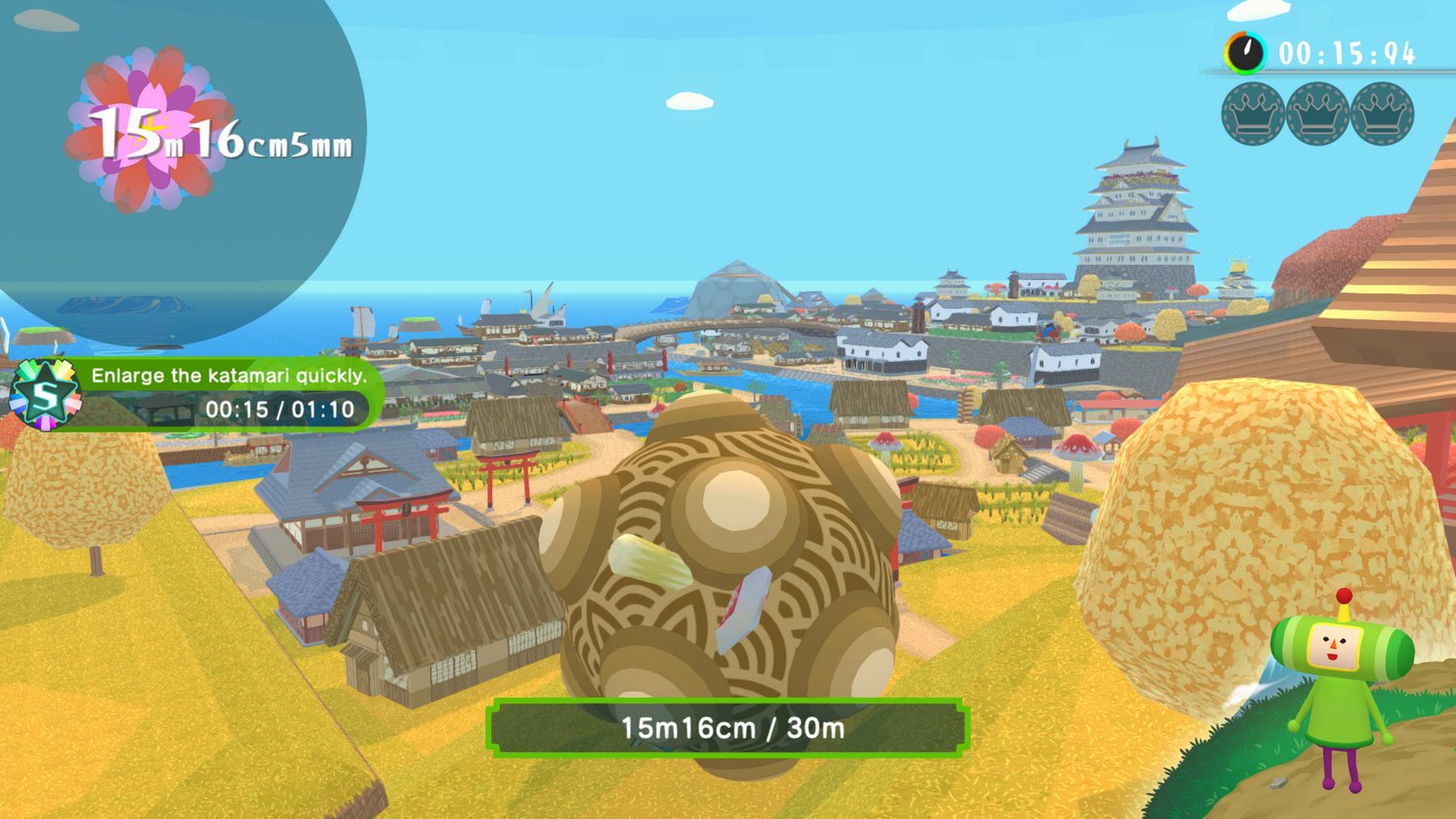 Una escena de juego con una gran bola recogiendo objetos. Un pueblo con un castillo al fondo y un personaje en primer plano.