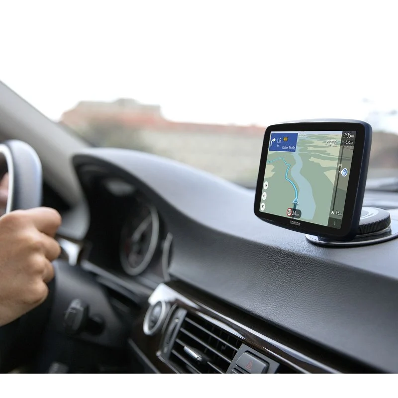 Un dispositivo GPS con un mapa se monta en el salpicadero de un coche. Una mano sujeta el volante. El interior del coche es visible.