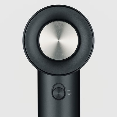 Zbliżenie czarnej i srebrnej suszarki do włosów. Suszarka ma okrągłą głowicę z metalowym środkiem i przyciskiem sterowania.