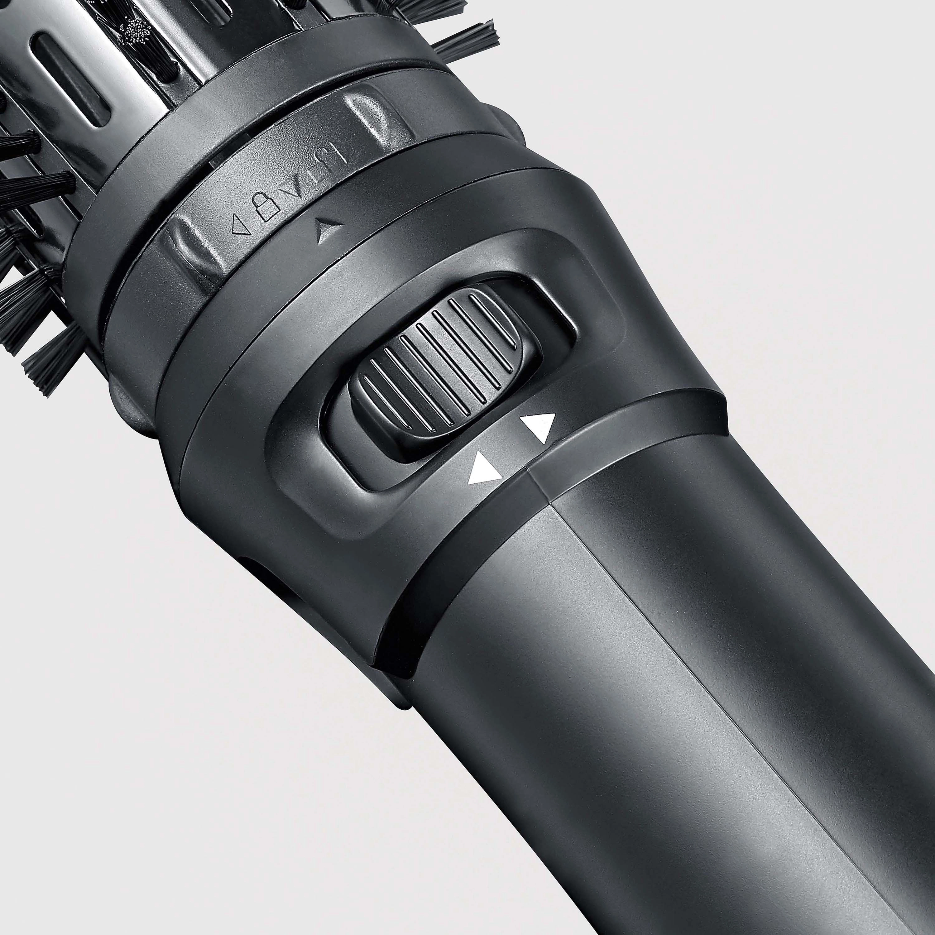 Zbliżenie czarnego narzędzia do stylizacji włosów. Ma obracającą się głowicę z włosiem i przełącznik sterowania.