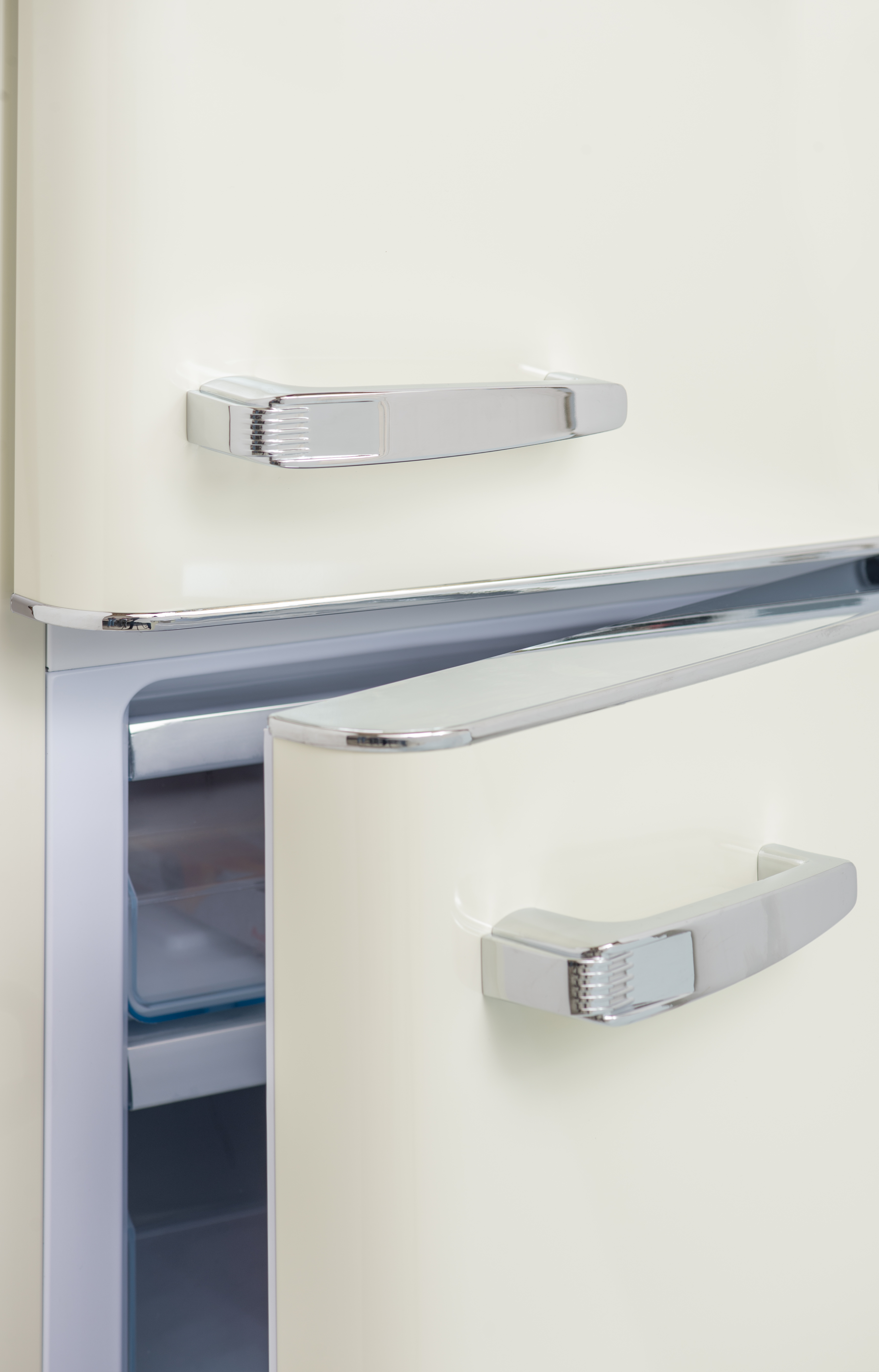 Cremefarbener Retro-Kühlschrank mit halb geöffneter Tür. Chromgriffe und -verkleidungen sind sichtbar.