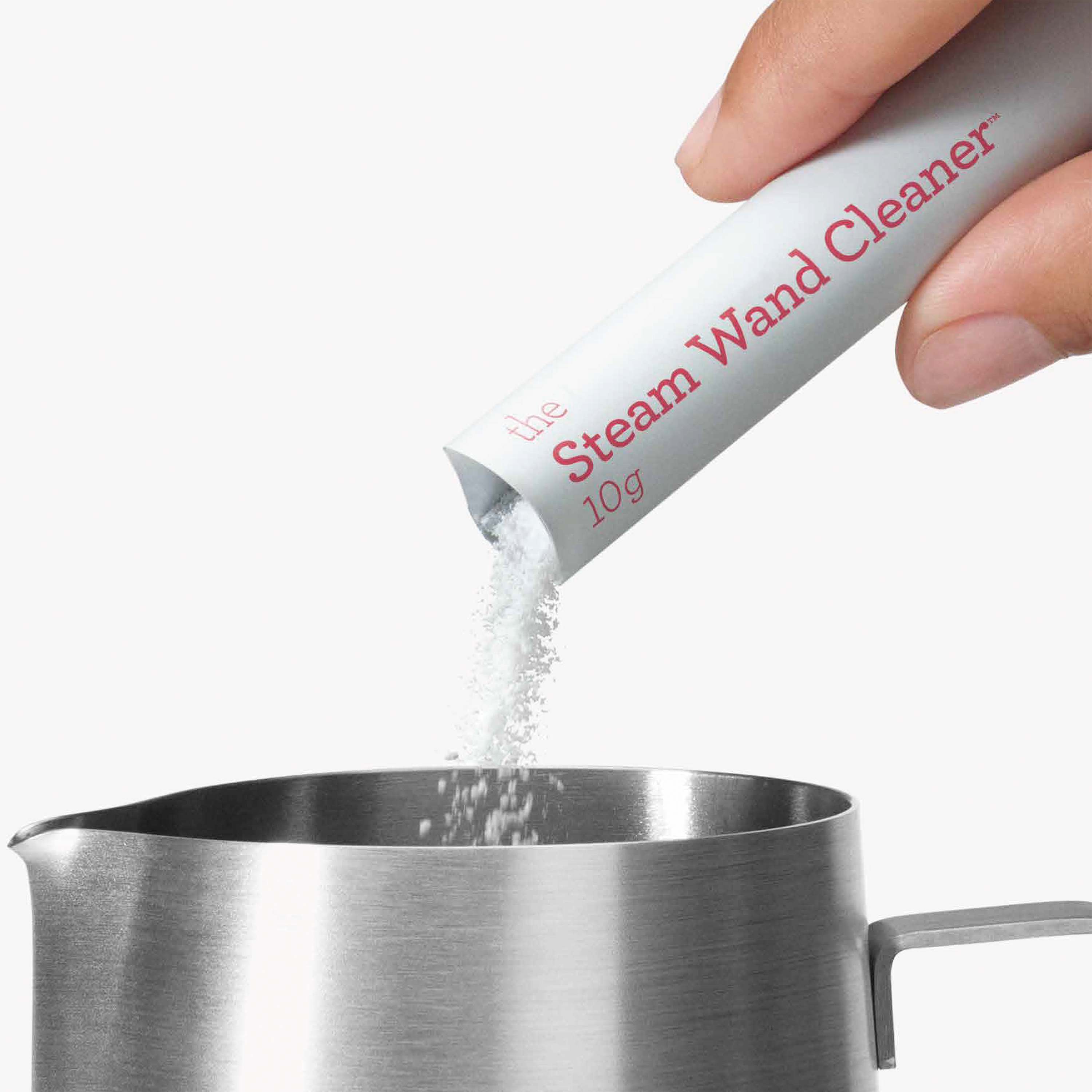 Eine Hand gießt Dampfstab-Reinigerpulver aus einer Packung in einen Edelstahlkrug.