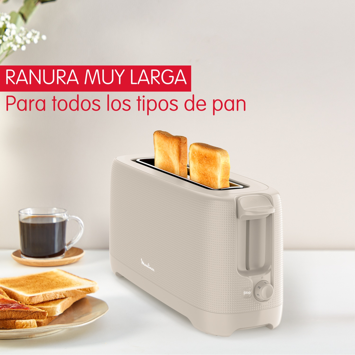 Un grille-pain beige avec deux tranches de pain grillé. Une tasse de café et des toasts à la confiture sont sur la table.